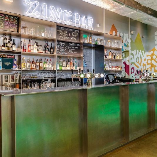 The bar at Zinc Bar in ClinkNOORD hostel in Amsterdam, stocked with beers, wines, spirits, soft drinks and glassware.