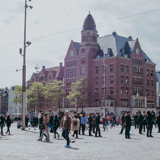 People walking and gathering at Dam Square in Amsterdam City Centre, in front of Gassan Diamonds.
