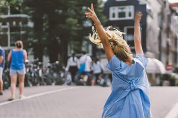 glückliches Mädchen, das an einer Amsterdamer Gracht entlang hüpft