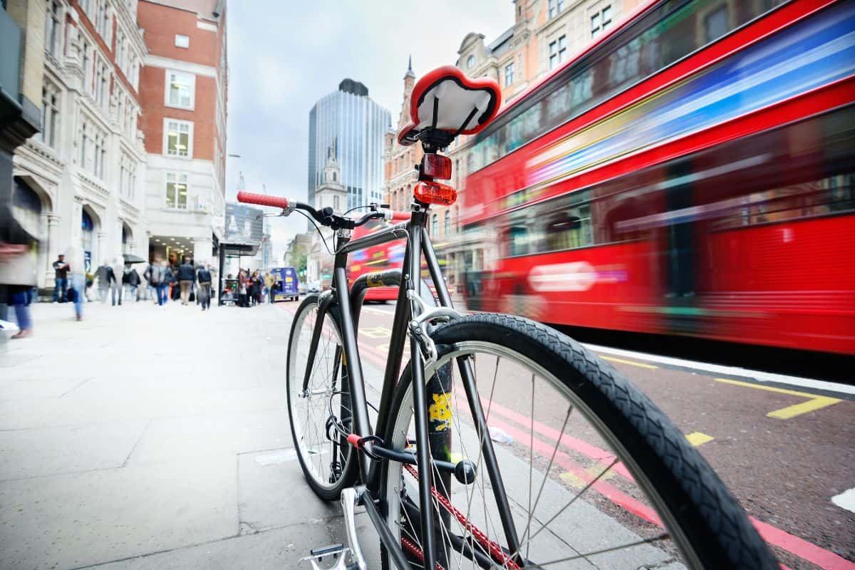 a bike and red bus on a main street in london