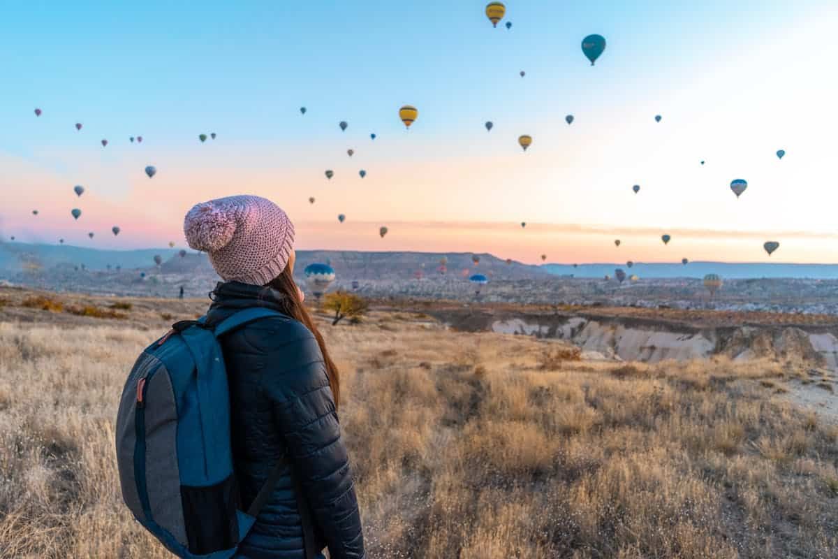 Woman with a backpack watching hot air balloons in the sky