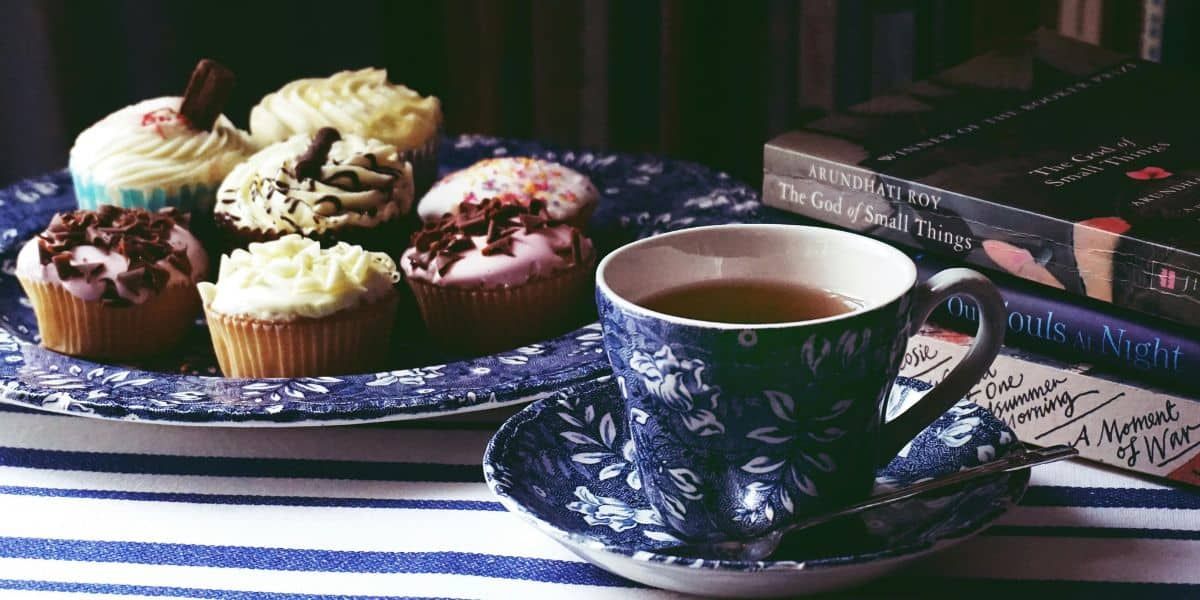 plate of cupcakes with a mug of tea and books on the side