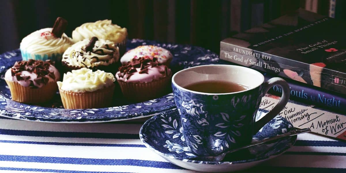 plate of cupcakes with a mug of tea and books on the side