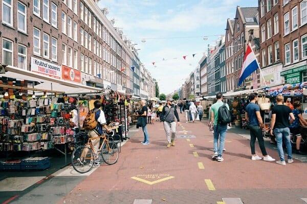 people walking past outdoor market stalls 