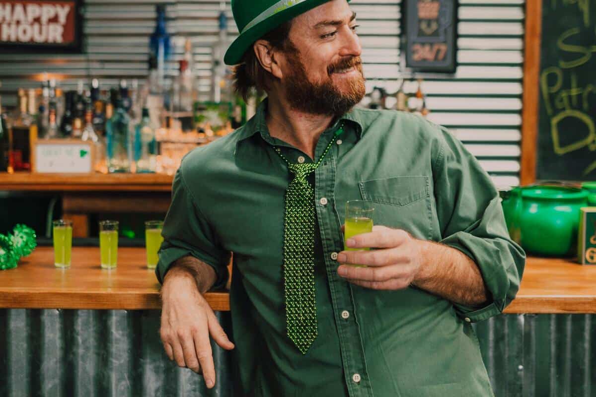 A man holding a shot in his hand, smirking