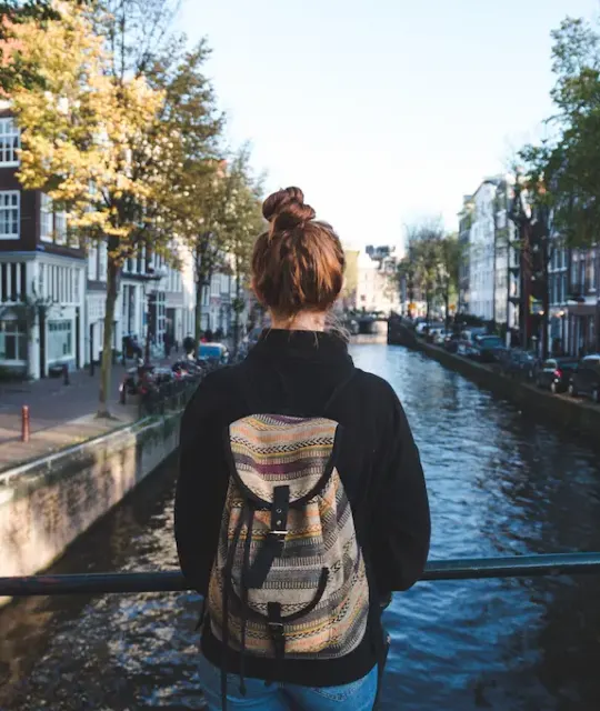 Backpacker looking out over an Amsterdam canal lined with houses