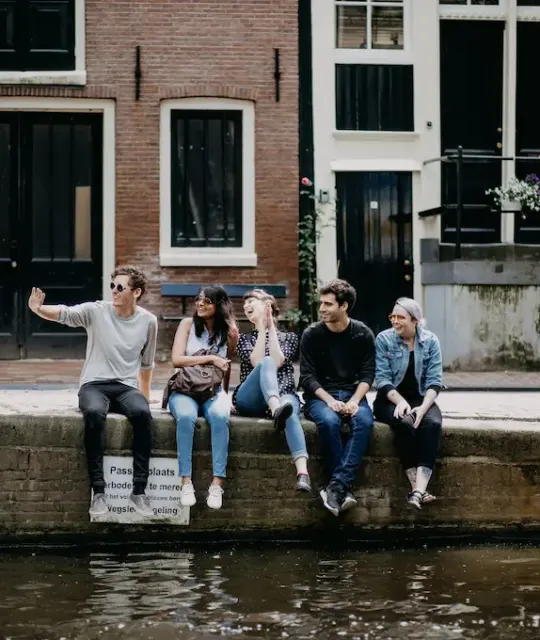 Group of friends sitting together by an Amsterdam canal