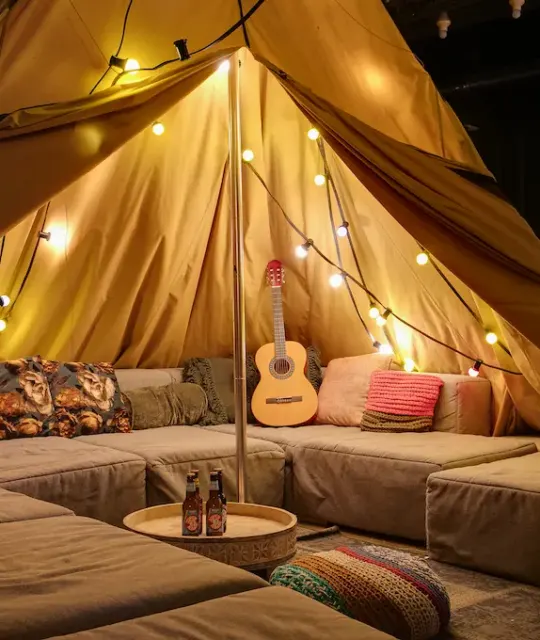 Gemütliches Indoor-Zelt mit Kissen, Lichterketten und einer Gitarre im ClinkMama, Amsterdam