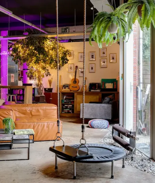 Lounge mit Ledersofas, Pflanzen und einer Hängeschaukel im ClinkMama, Amsterdam
