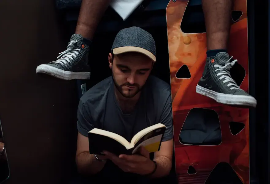 Un hombre leyendo un libro en un dormitorio de albergue