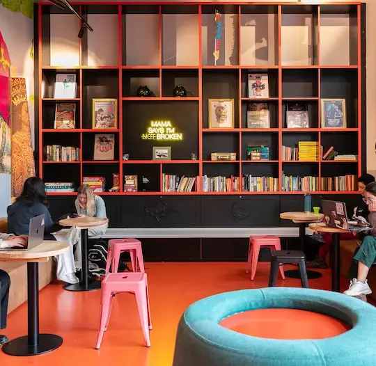 Common room with bookshelves and people on laptops at Clink i Lar, Dublin