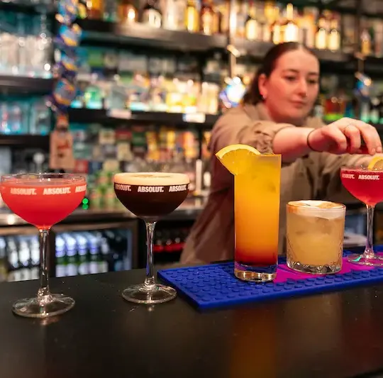 Bartender garnishing a row of cocktails at the Clink i Lar bar, Dublin