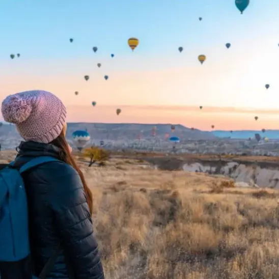 Woman with a backpack watching hot air balloons in the sky