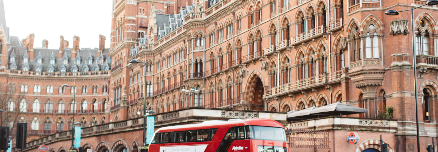 A red London double-decker bus outside King's Cross / St. Pancras station.