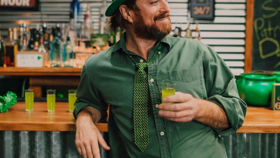 A man holding a shot in his hand, smirking