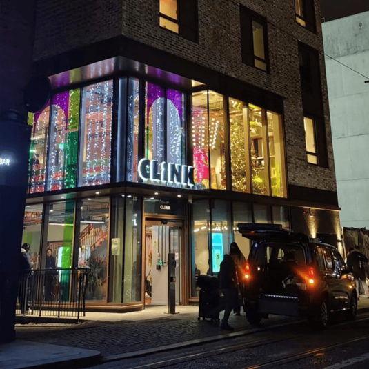 Clink hostel from outside lit up with lights at night